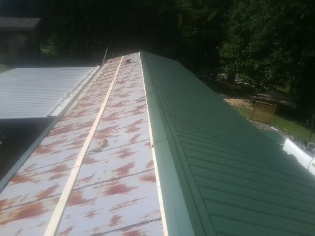 Old rusted panels beside newly installed green metal roofing — Wind Damage Roof Repair by Roofing Brothers in Bountiful