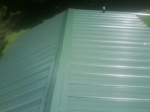 New green metal panels meeting at the ridge of a roof — Flat Roof Repair work by our crew in Bountiful