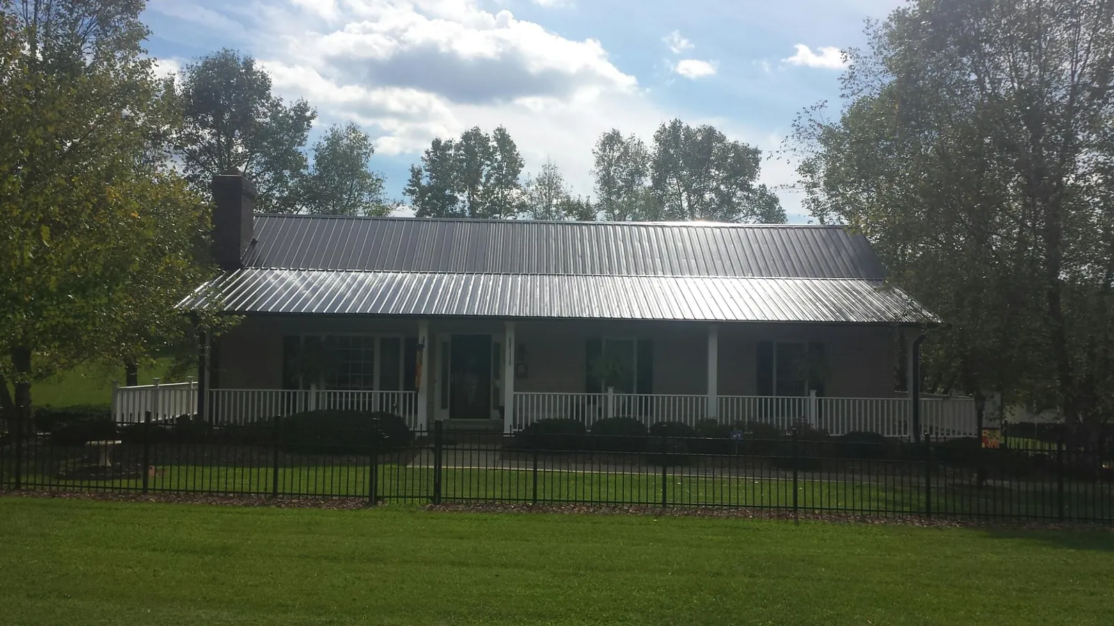 Gray metal roof on a brick ranch with a full width front porch — Gutter Guard Installation work by our crew in Bountiful