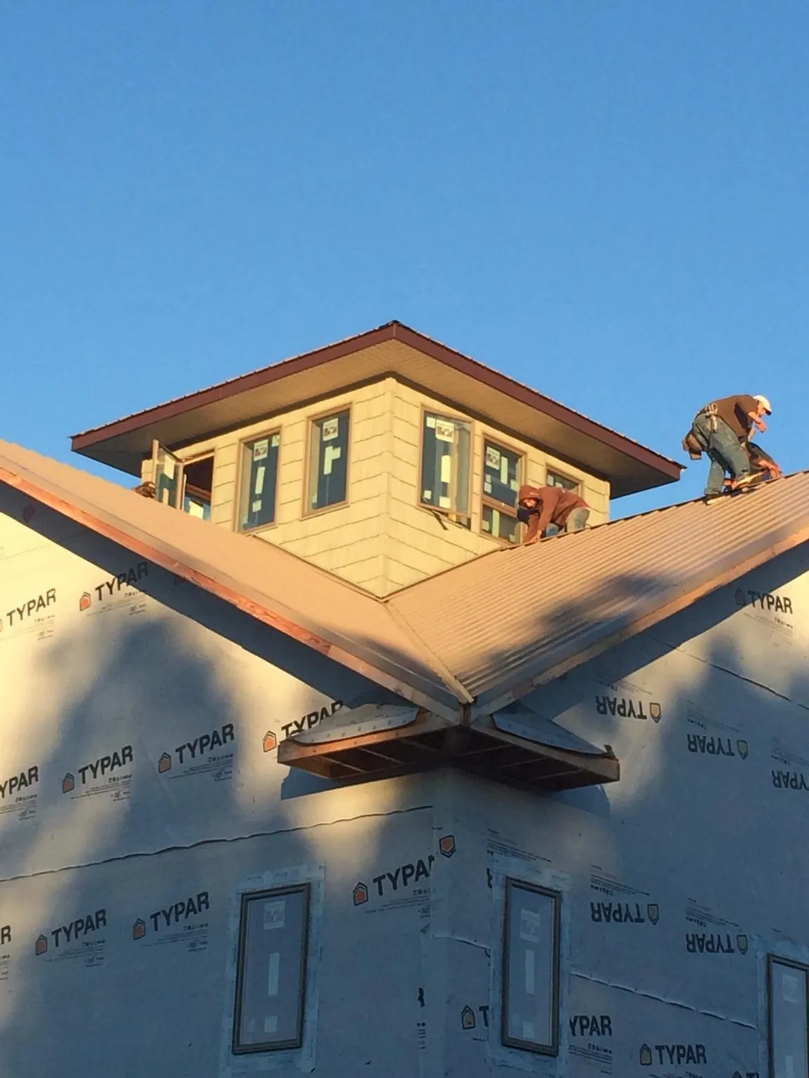 Roofers working around a rooftop cupola on a new metal roof at sunset — Roof Waterproofing in Bountiful by Roofing Brothers